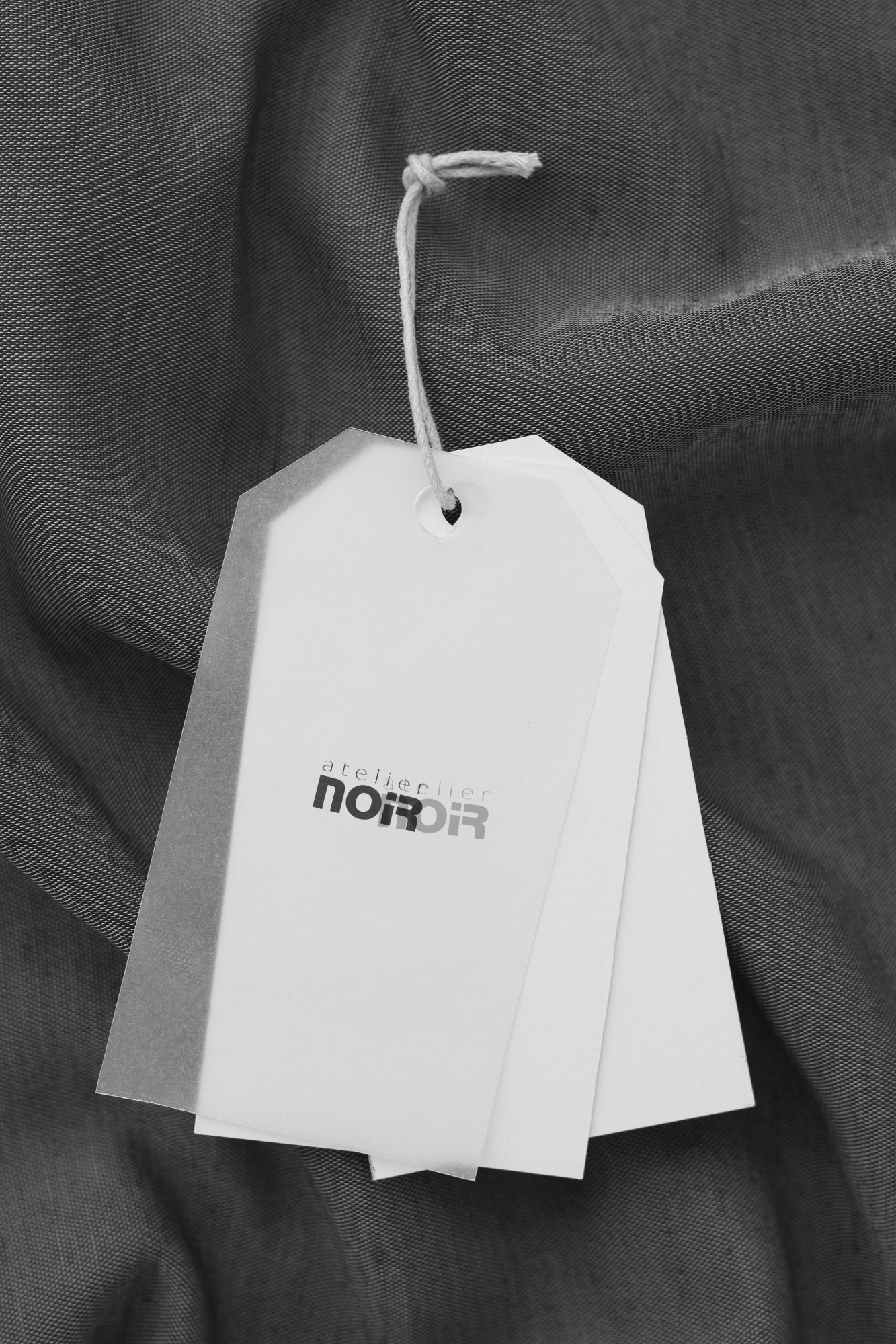 Этикетка с логотипом Atelier NOIR на темном тканевом фоне, минималистичный брендинг